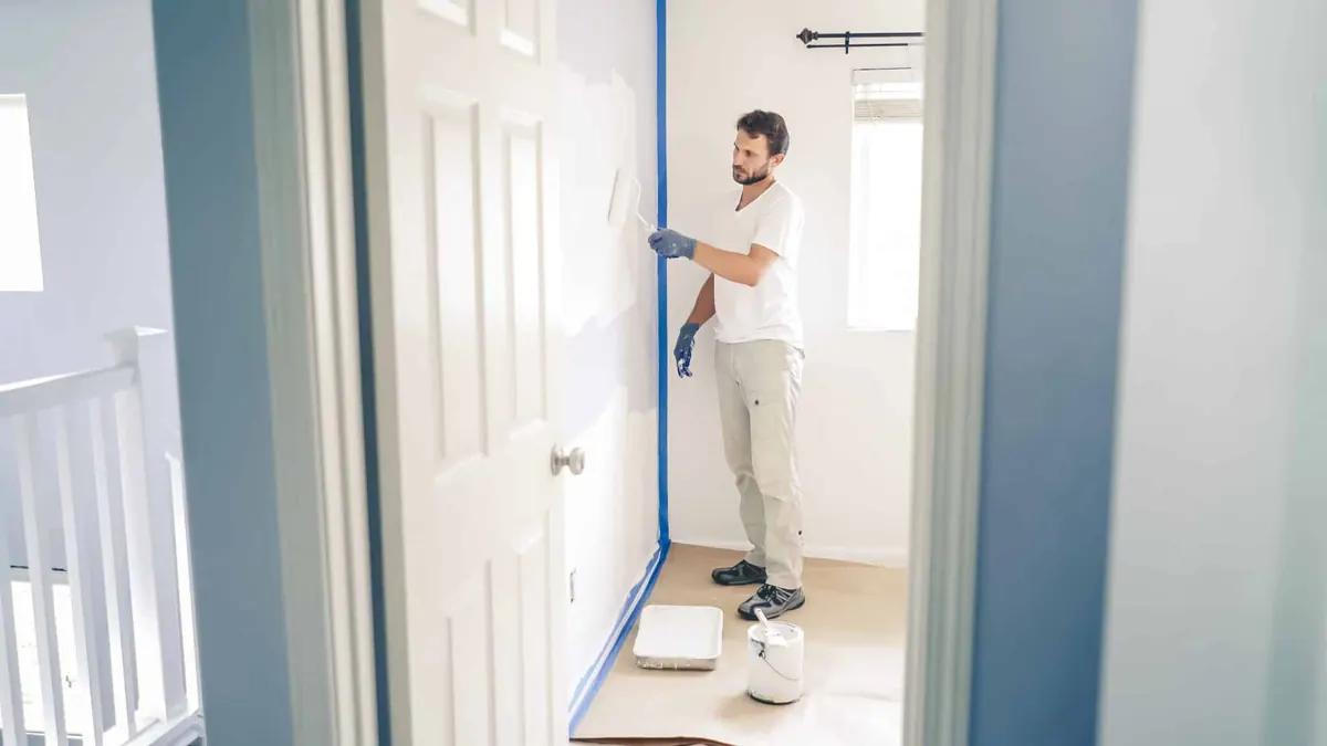 Maler arbejder ved en blå endevæg i et værelse